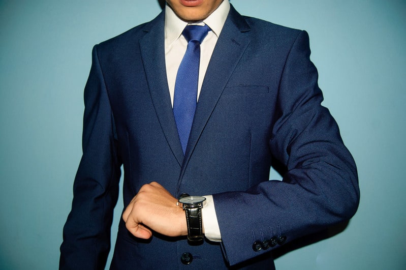 腕時計を見るスーツ姿の男性