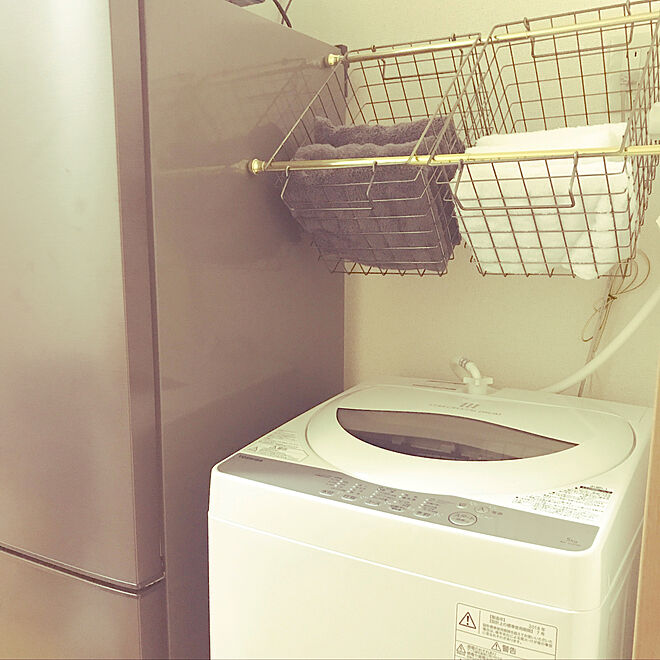 洗濯機上につっぱり棒を付けて収納スペースを作っている例