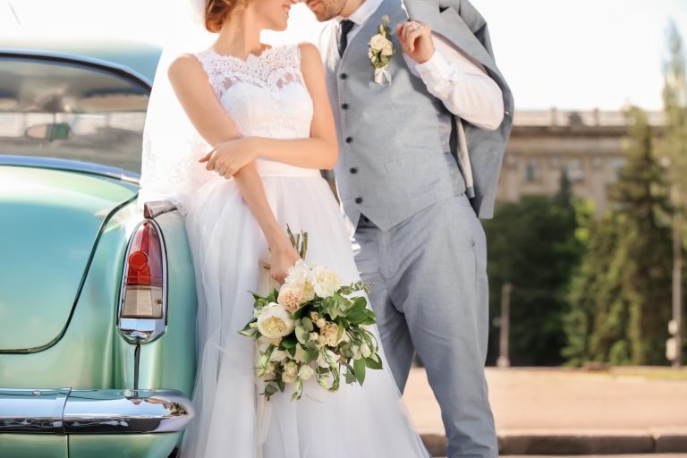 Happy wedding couple near car outdoors