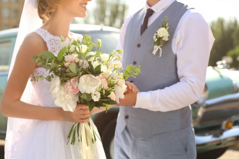 Happy wedding couple and car on background