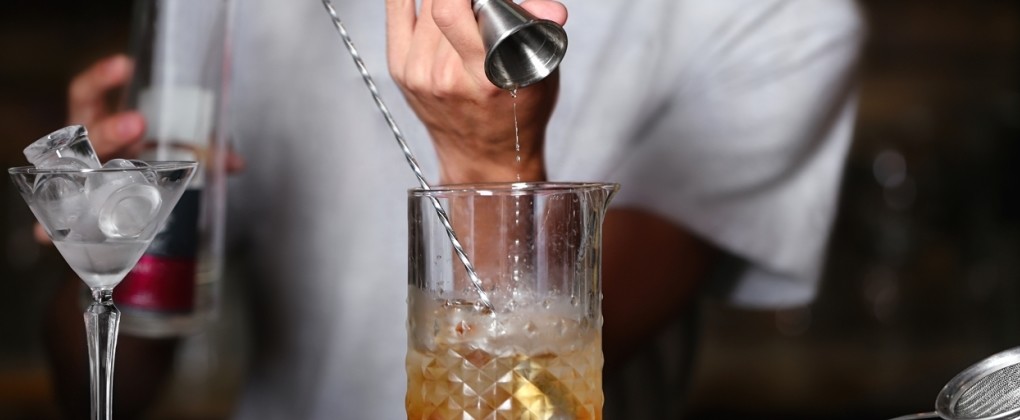 カウンターでカクテルを作るバーテンダー
